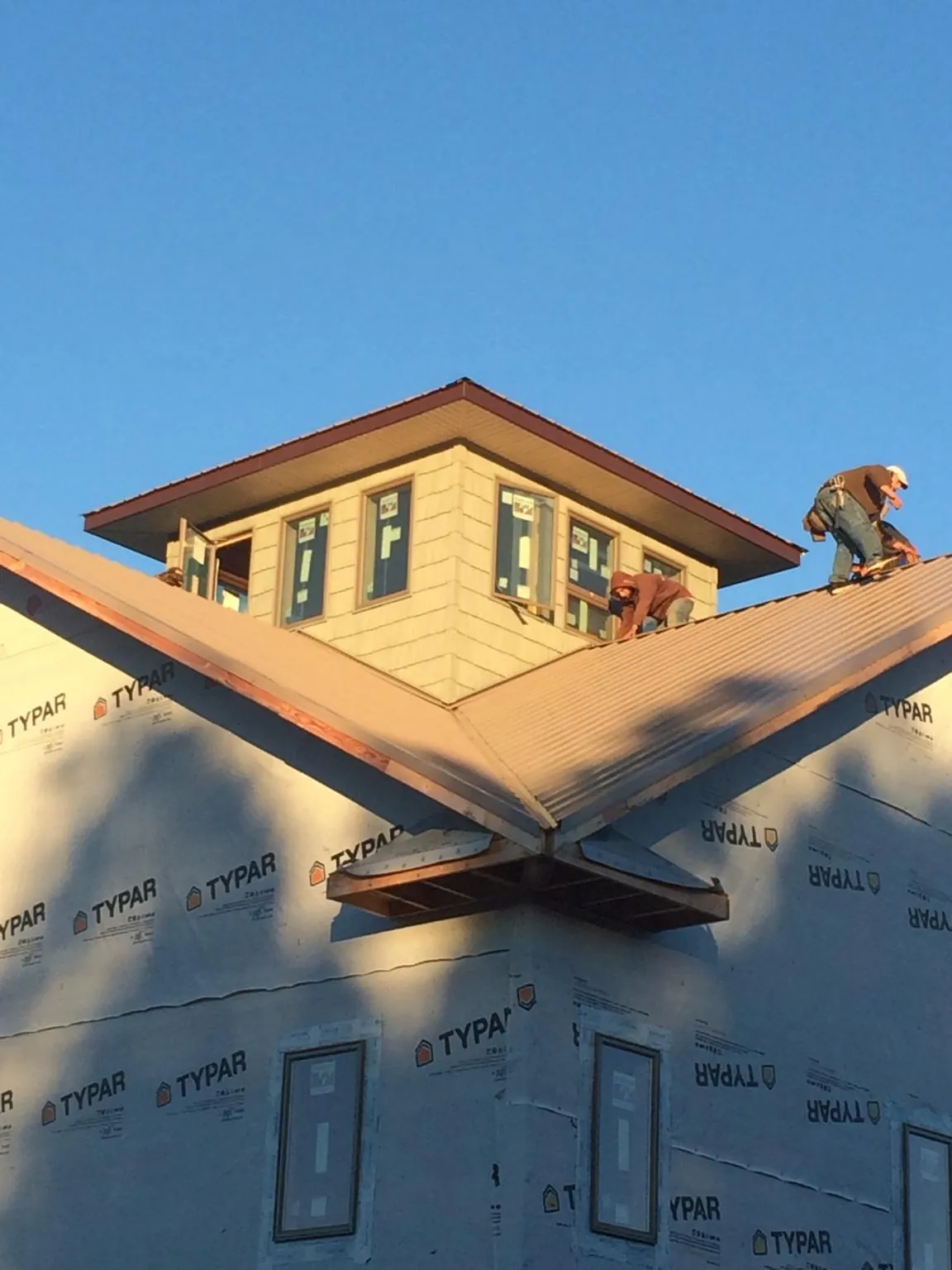 Roofers working around a rooftop cupola on a new metal roof at sunset — Roof Waterproofing in Danbury by Roofing Brothers